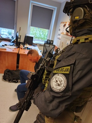 policjant stoi obok zatrzymanego.