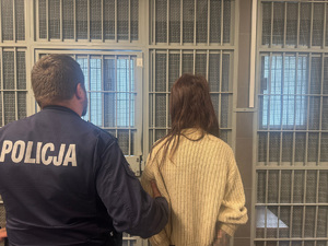 Umundurowany policjant prowadzi zatrzymaną.