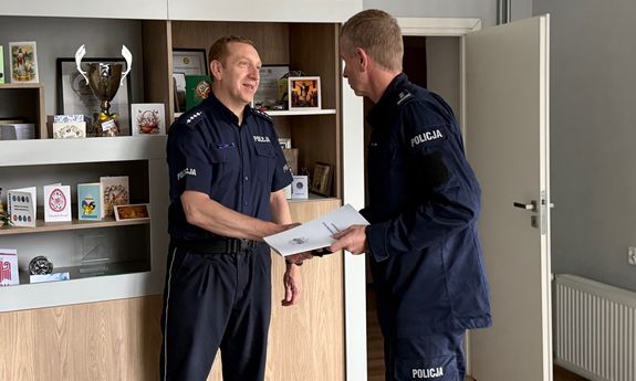 Umundurowany policjant ściska dłoń drugiemu policjantowi.