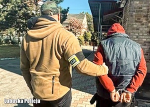 Zatrzymany mężczyzna prowadzony przez nieumundurowanego policjanta.