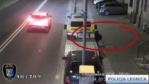 kadr z monitoringu, mężczyzna próbuje włamać się do samochodu i ucieka widząc policję.