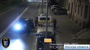 kadr z monitoringu, mężczyzna próbuje włamać się do samochodu i ucieka widząc policję.