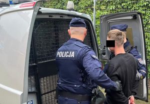 policjanci stoją z zatrzymanym.
