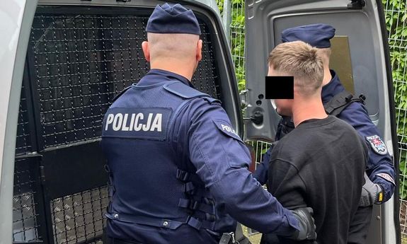 policjanci stoją z zatrzymanym.
