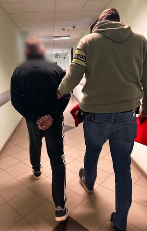 policjanci idą z zatrzymanym.
