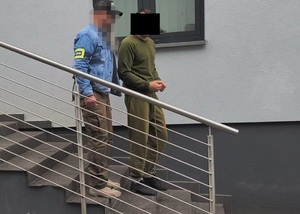 Policjanci prowadzą zatrzymanego mężczyznę.
