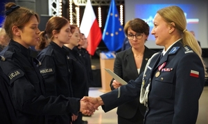 Policjanci i zatrzymane osoby przy samochodzie osobowym.