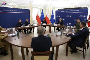 Uczestnicy odprawy służb siedzą przy stole obrad.