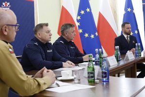 Uczestnicy odprawy służb siedzą przy stole obrad.