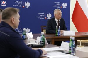 Uczestnicy odprawy służb siedzą przy stole obrad.