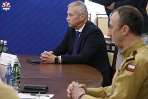 Uczestnicy odprawy służb siedzą przy stole obrad.