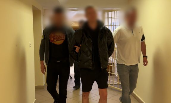 Dwaj nieumundurowani policjanci prowadzą zatrzymanego.