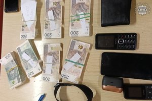 Zabezpieczona gotówka, telefony i pasek leżą ułożone na stoliku.