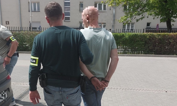 Policjant prowadzi zatrzymanego.