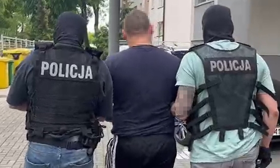 Dwaj policjanci prowadzą zatrzymanego.