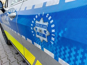 Hasło pomagamy i chronimy na niebieskim tle pasa bocznego radiowozu.