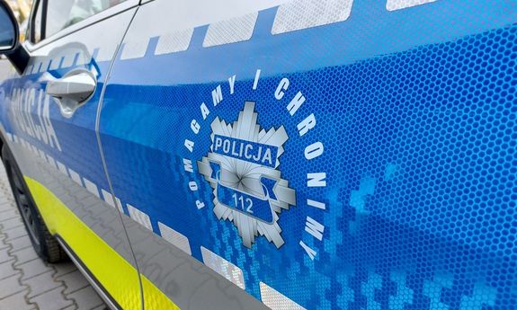 Hasło pomagamy i chronimy na niebieskim tle pasa bocznego radiowozu.