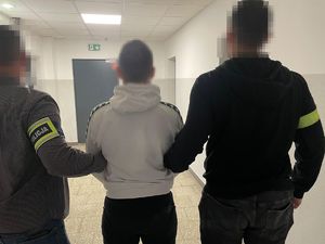 policjanci idą z zatrzymanym.