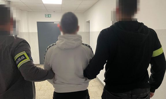 policjanci idą z zatrzymanym.