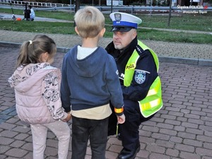Policjant kuca przy dwójce małych dzieci.