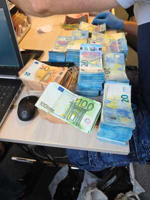 Banknoty euro na blacie obok laptopa.