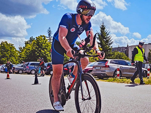 Zawodnik na rowerze na trasie triathlonu.