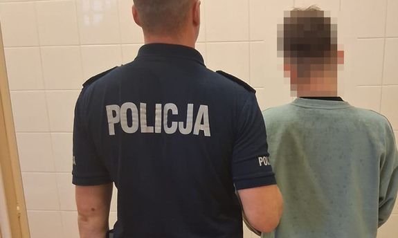 Umundurowany policjant stoi z zatrzymanym mężczyzna - widok z tyłu.