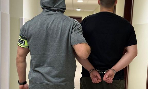 Nieumundurowany policjant z zatrzymanym - widok z tyłu.