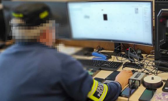 policjant siedzi przed komputerem.