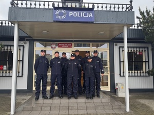 Policjanci stoją przy wejściu do budynku komisariatu.