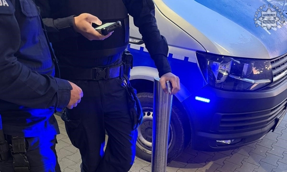 Dwaj funkcjonariusze przy radiowozie.