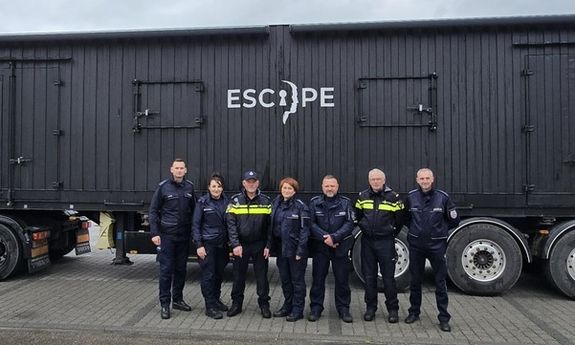 policjanci stoją przed przyczepą,