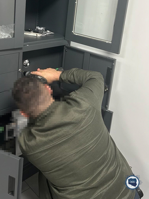 Policjant rozwierca zamek w sejfie.
