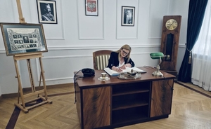 Kobieta siedzi przy biurku wpisując się do księgi.