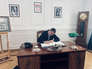 Mężczyzna siedzi przy biurku wpisując się do księgi.