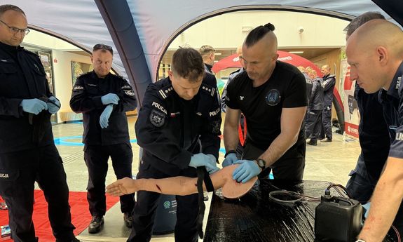 Szkoleniowiec pokazuje zebranym policjantom jak zatamować krwawienie.