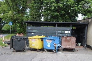 Spalona wiata śmietnikowa ,przy garażach i zaparkowane pojazdy.