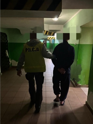Policjant prowadzi zatrzymanego.