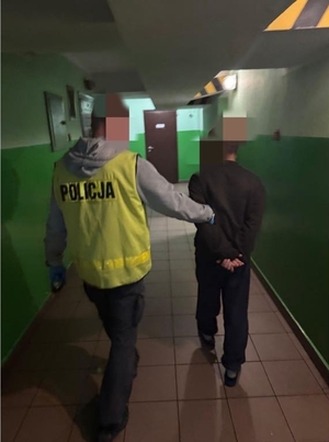 Policjant prowadzi zatrzymanego.
