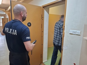 Policjant wprowadza zatrzymanego do aresztu.