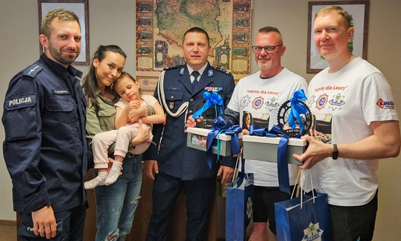 Dwaj policjanci, kobieta z dzieckiem na rękach i dwaj mężczyźni.