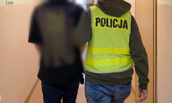 Funkcjonariusz prowadzi zatrzymanego.