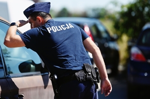 Policjant sprawdzający czy wewnątrz auta nie ma pozostawionych dzieci lub zwierząt.