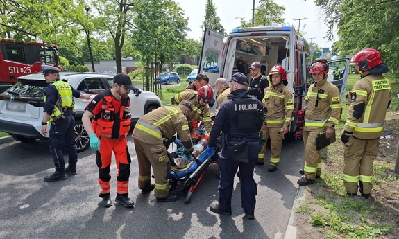 Służby ratunkowe pracują na miejscu wypadku z udziałem motocyklisty.