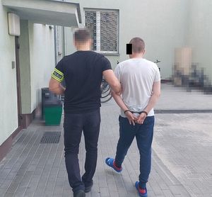 Policjant prowadzi zatrzymanego.