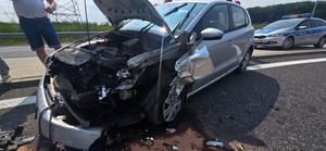 Rozbite auto na drodze. Z tyłu widoczny jest policyjny radiowóz.