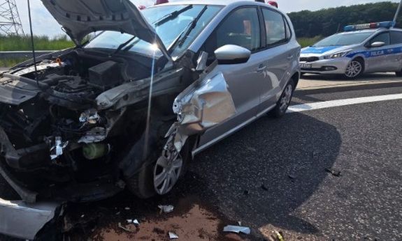 Rozbite auto na drodze. Z tyłu widoczny jest policyjny radiowóz.