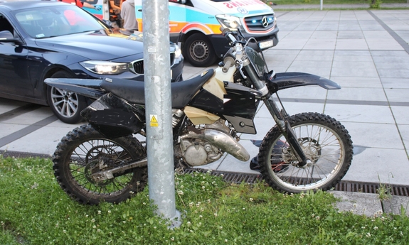 Motocykl stoi oparty o latarnię. w tle samochody.