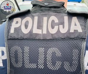 Odwrócony tyłem policjant. Na jego kamizelce znajduje się napis Policja.