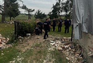 Policjanci sprzątają rozrzucone na posesji cegły, gałęzie, resztki dachów po przejściu nawałnicy.